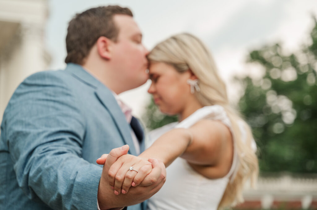 close up of ring on MIcheala's finger while Wade kisses her forehead