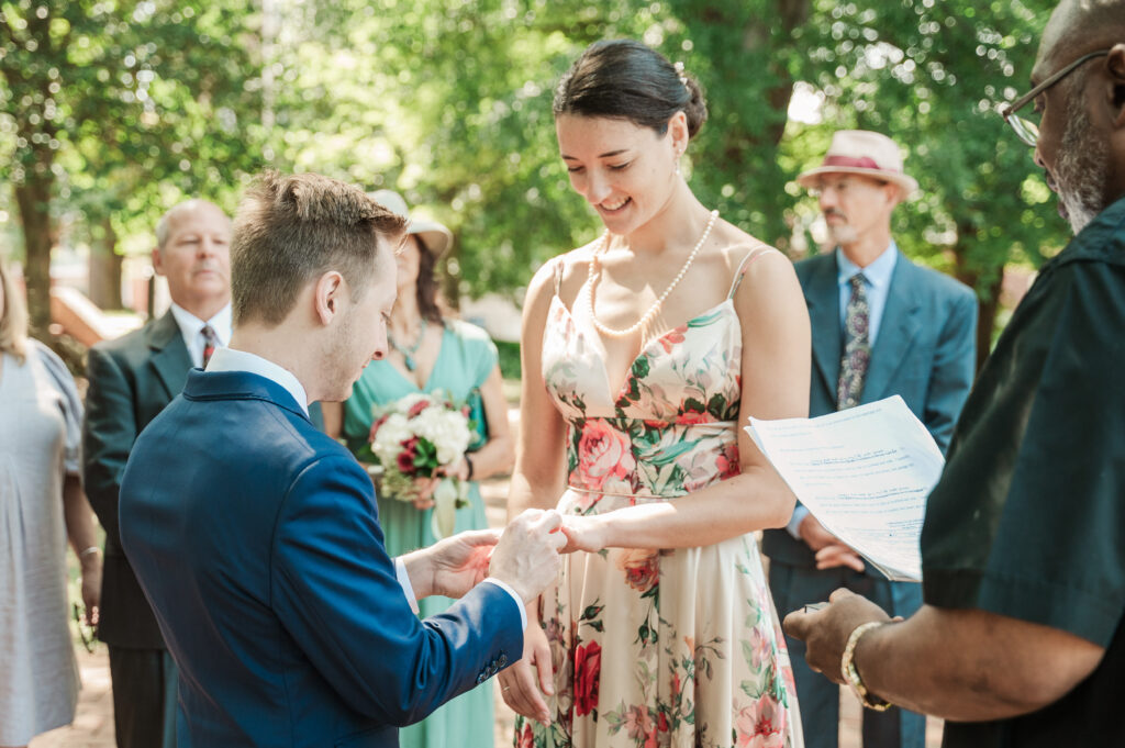 groom putting ring on bride's finger during their ceremony