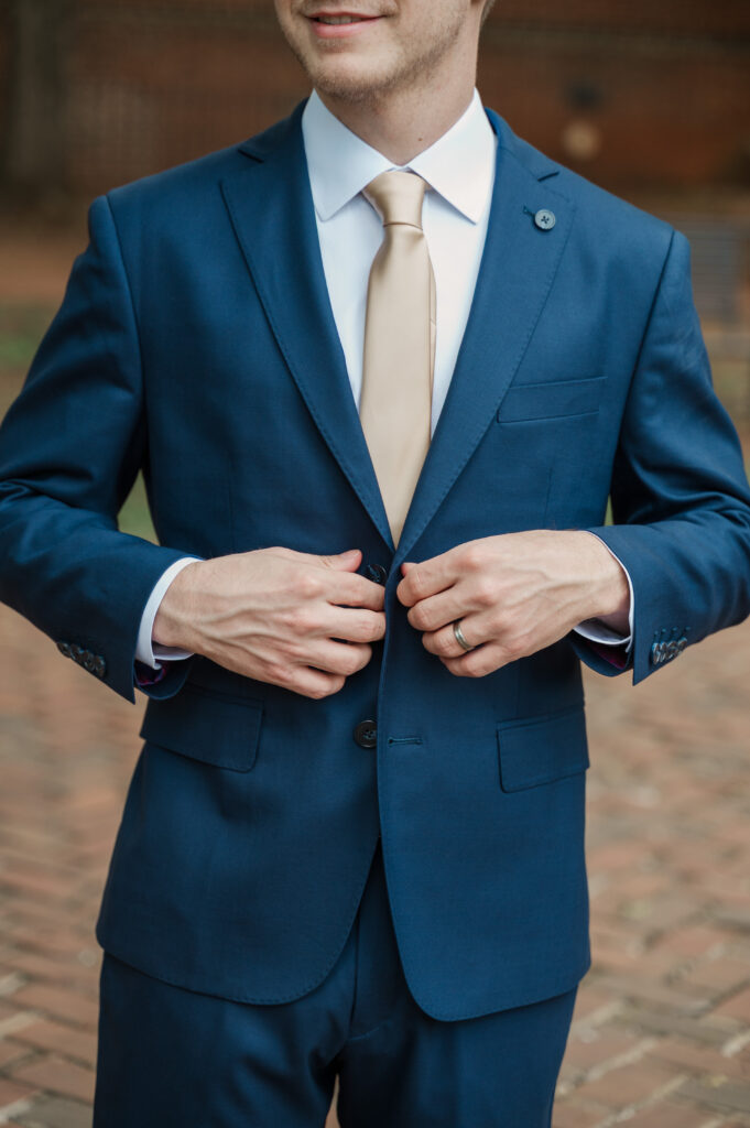 groom buttoning suit jacket