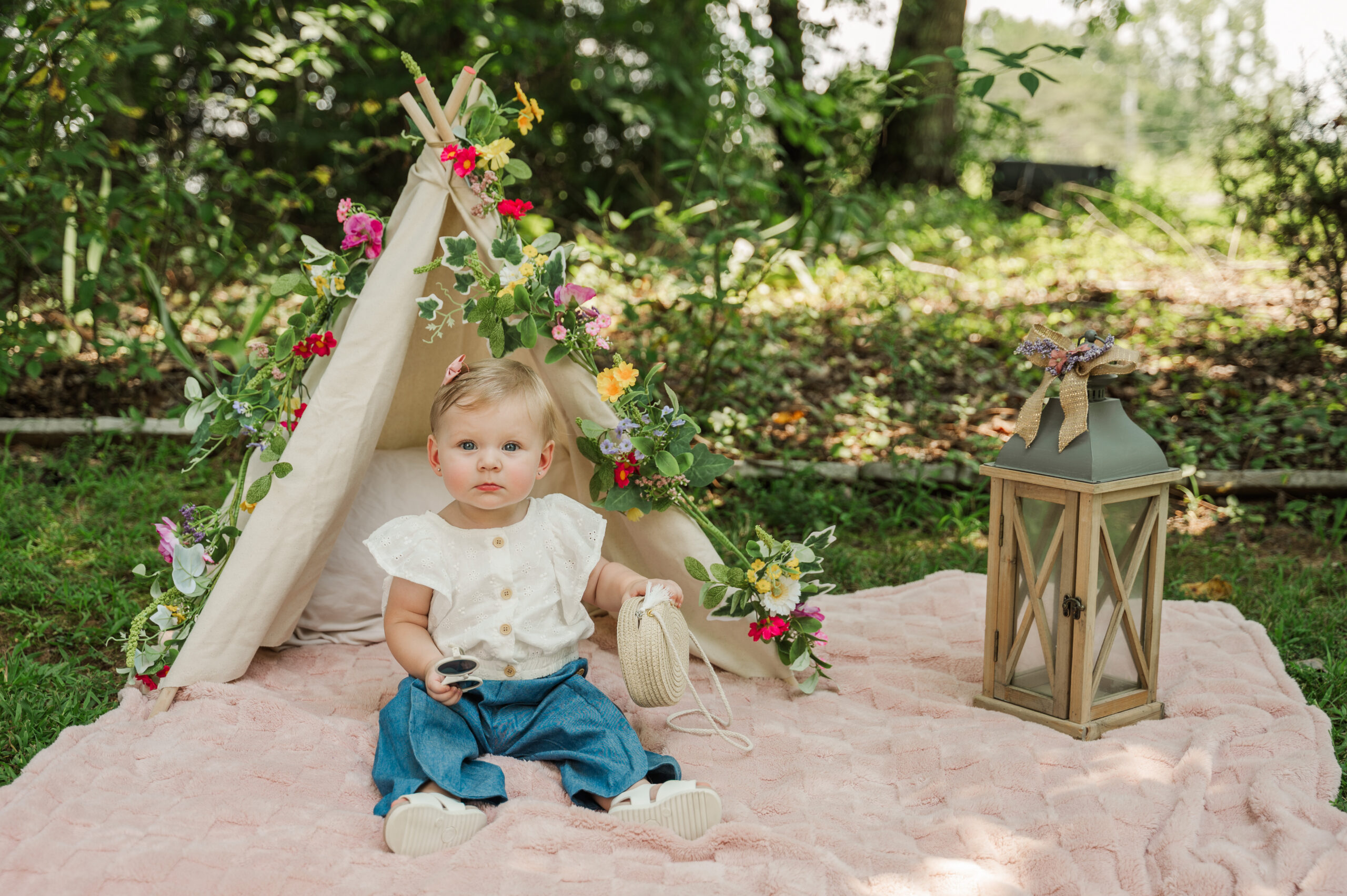 Teagan sitting on pink blanket with her teepee in the background