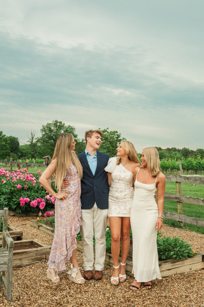 UVA graduates laughing with each other posing in front of peonies