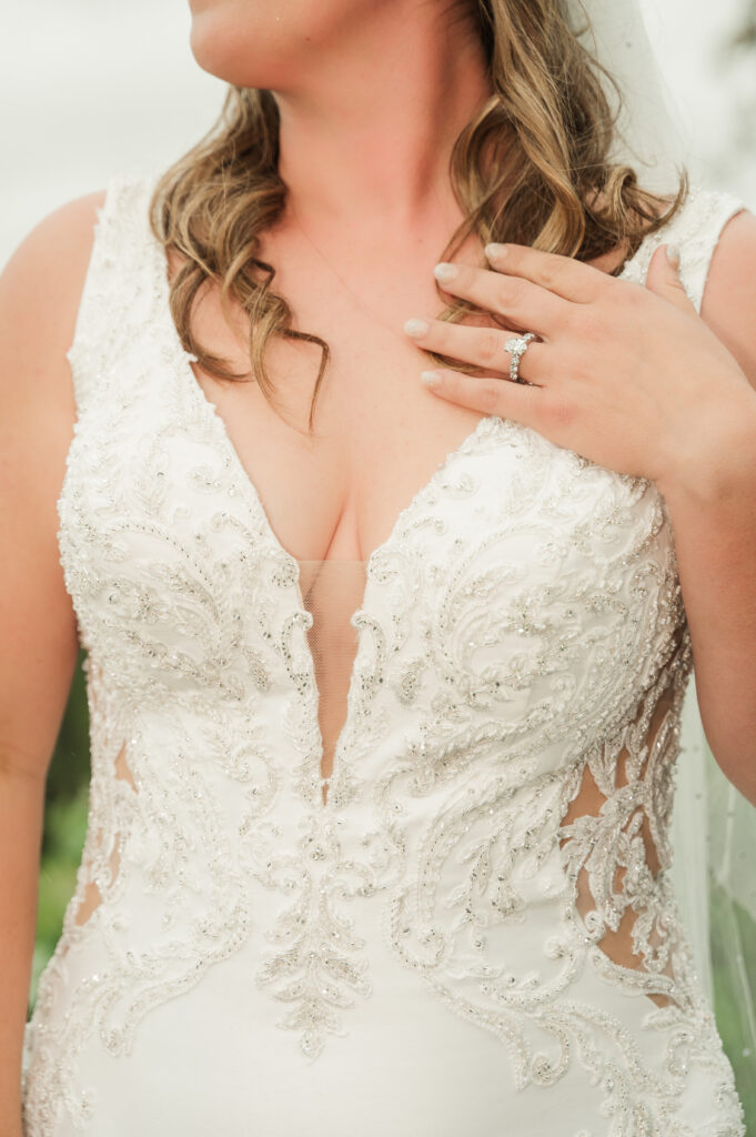 detail shot of the front of Kelly's dress and her hand with her engagement ring