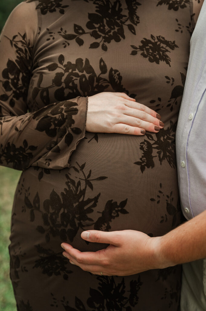 Close up of Emily and Derek's hands on their baby bump