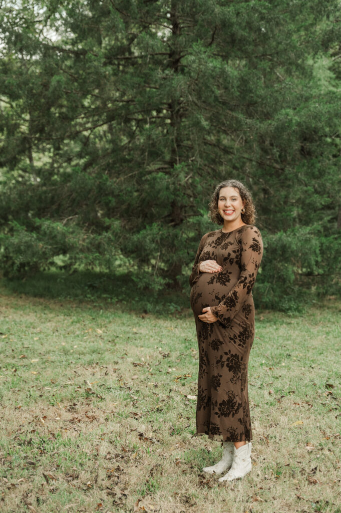 Pregnant Emily wearing a  brown fitted maternity dress and stylish white boots during her fall session at Saunders-Monticello Trail.
