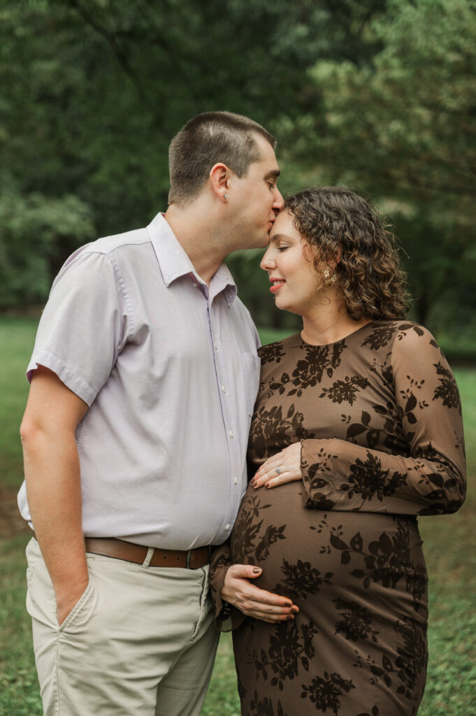 Derek kissing Emily's forehead during their maternity session at Saunders-Monticello Trail