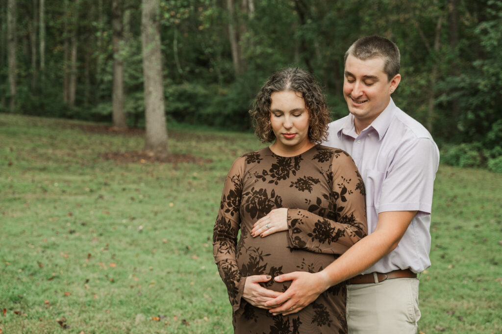 Emily and Derek focusing on her bump during their maternity session