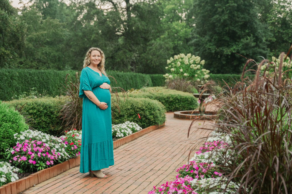 Moody and romantic maternity portrait of an expecting mother in a green park setting.