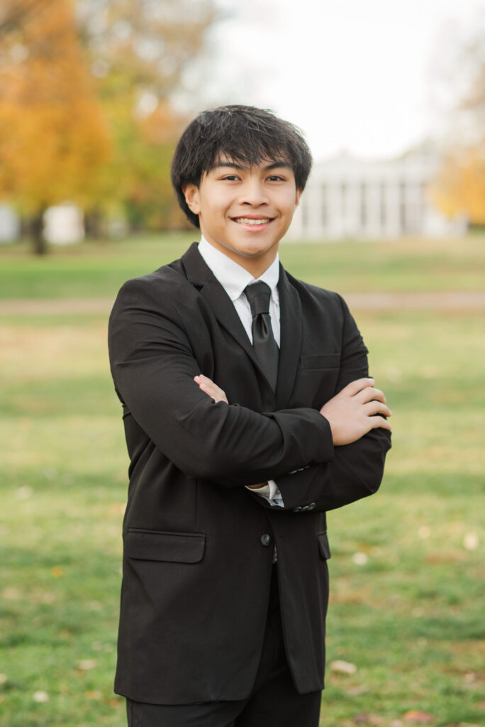 senior standing on lawn with arms crossed smiling