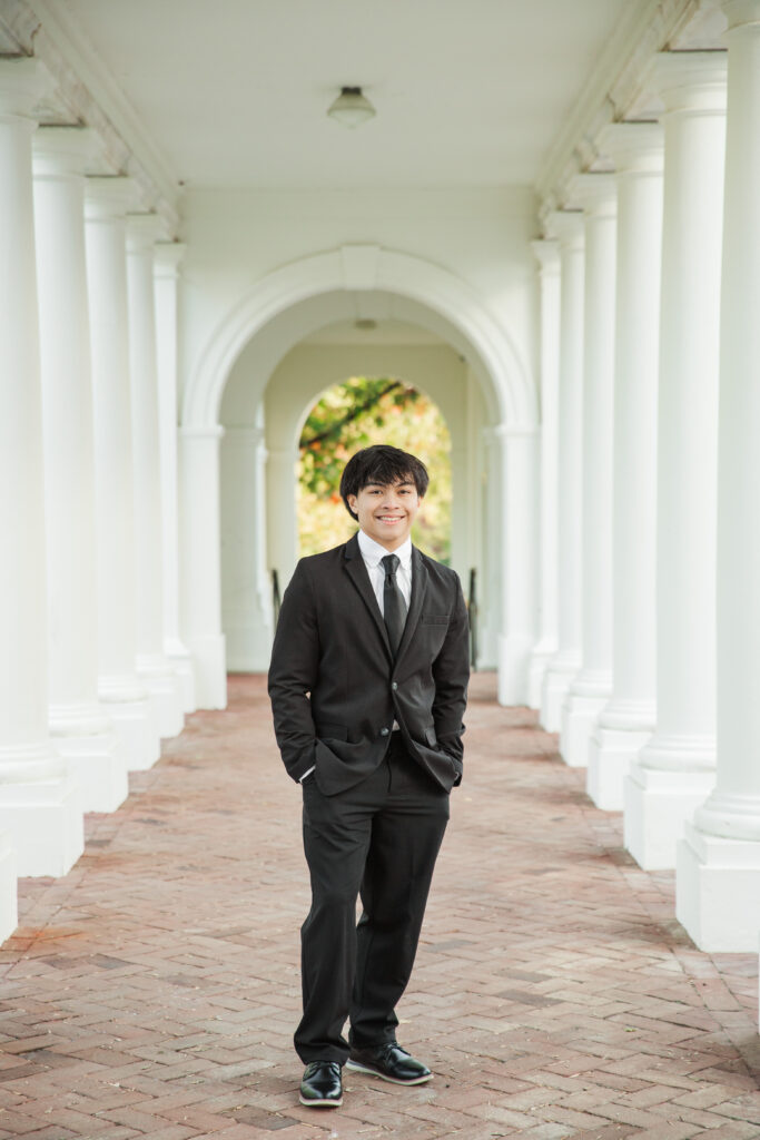 Senior standing under portico in archway between the columns at UVA
