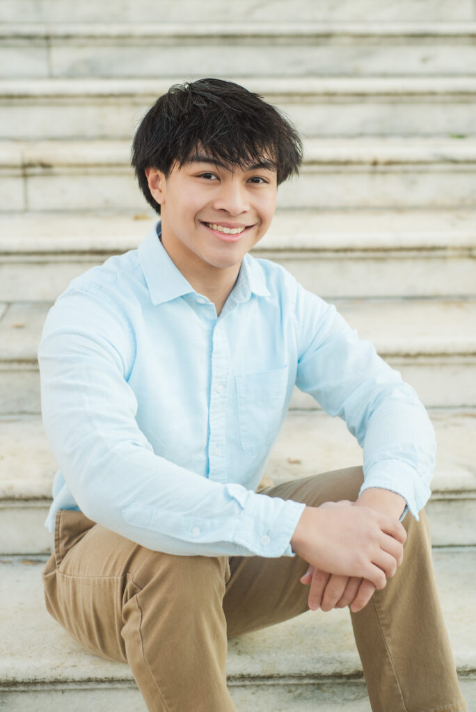 Connor sitting on steps with hands clasped on knees