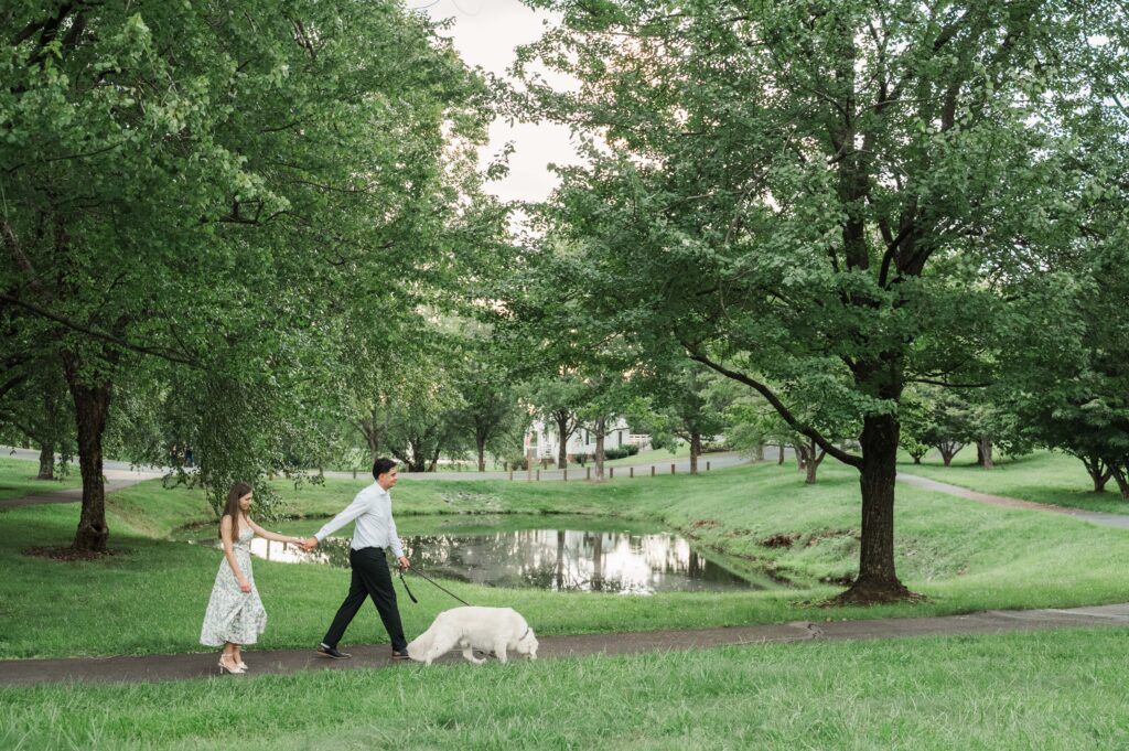 couple walking Duke in front of small pond  in park at Pantops