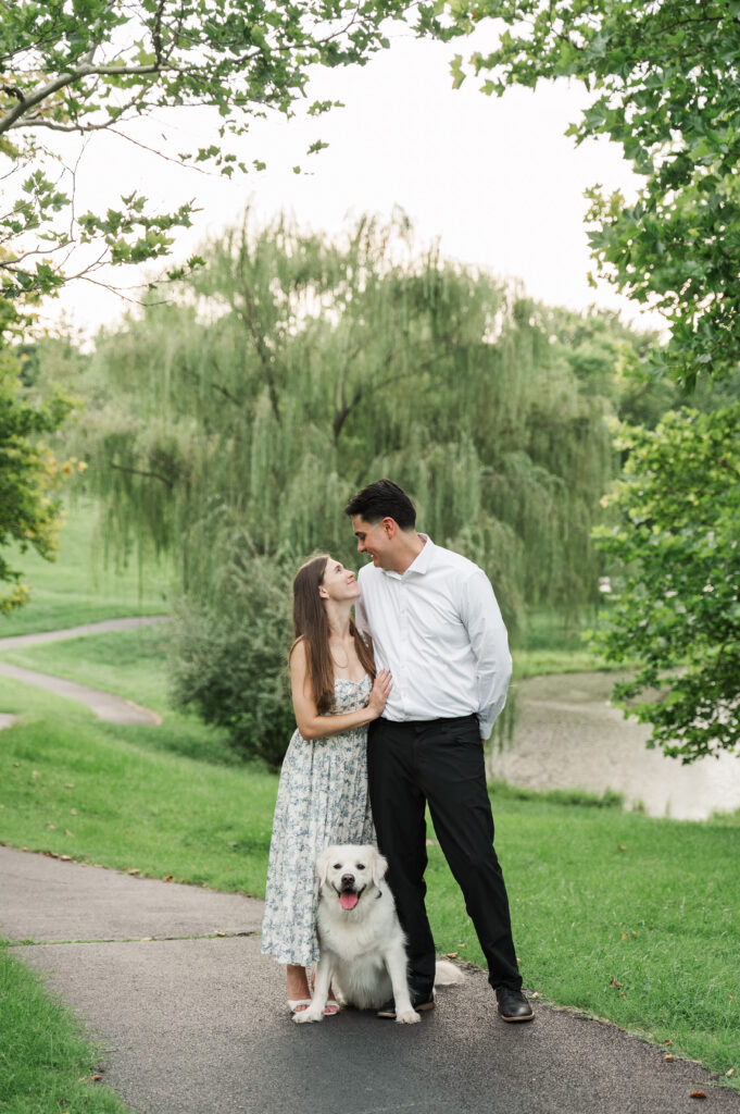couple gazing at each other with Duke sitting between them on path in park