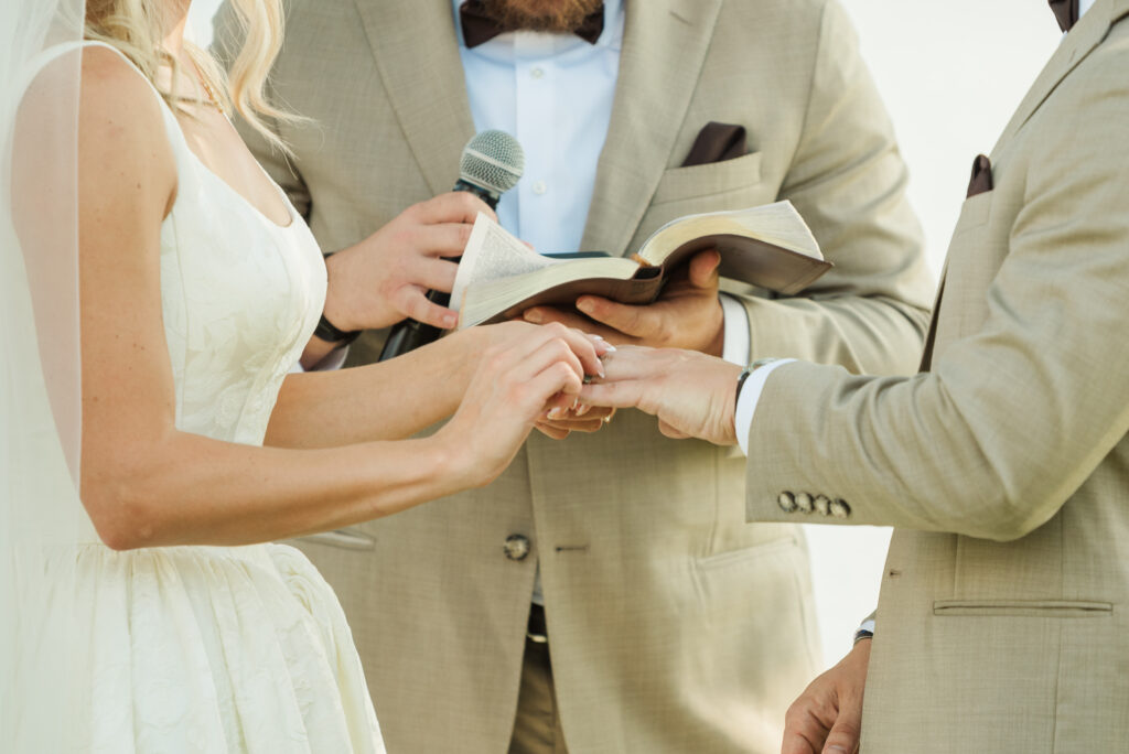 bride placing ring on groom's hand