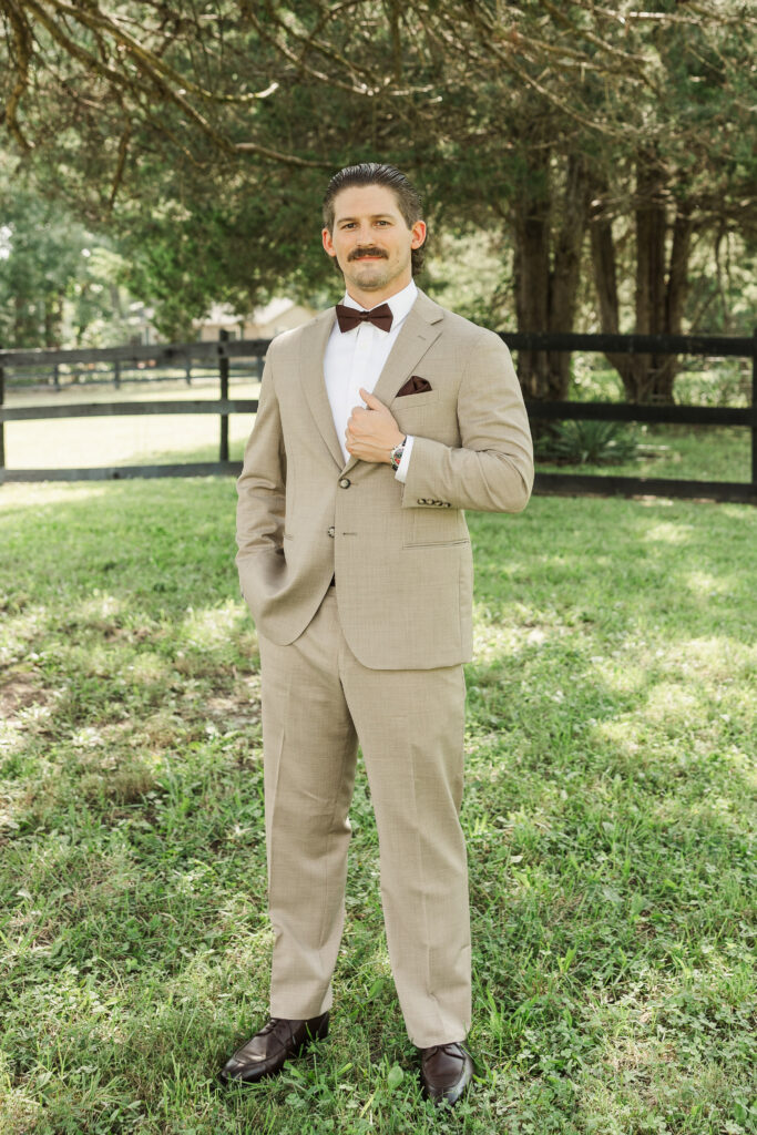 groom's portrait in yard in front of wooden fenc