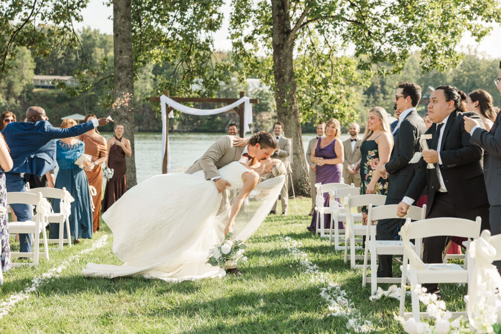 groom dipping the bride as they walk down the aisle