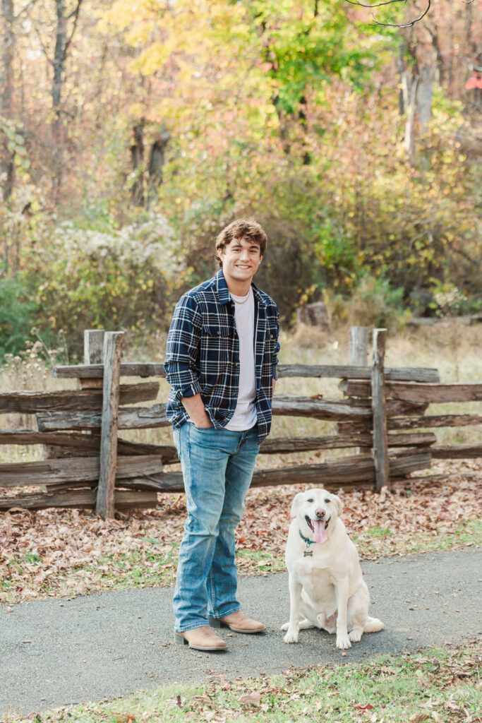 Nicholas standing with his labrador retriever in front of fence