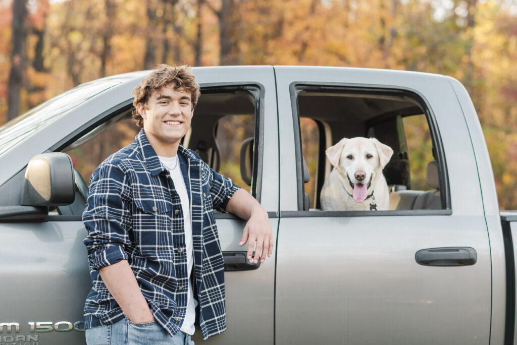 Nicholas posing with his labrador retriever sitting in his Dodge Truck