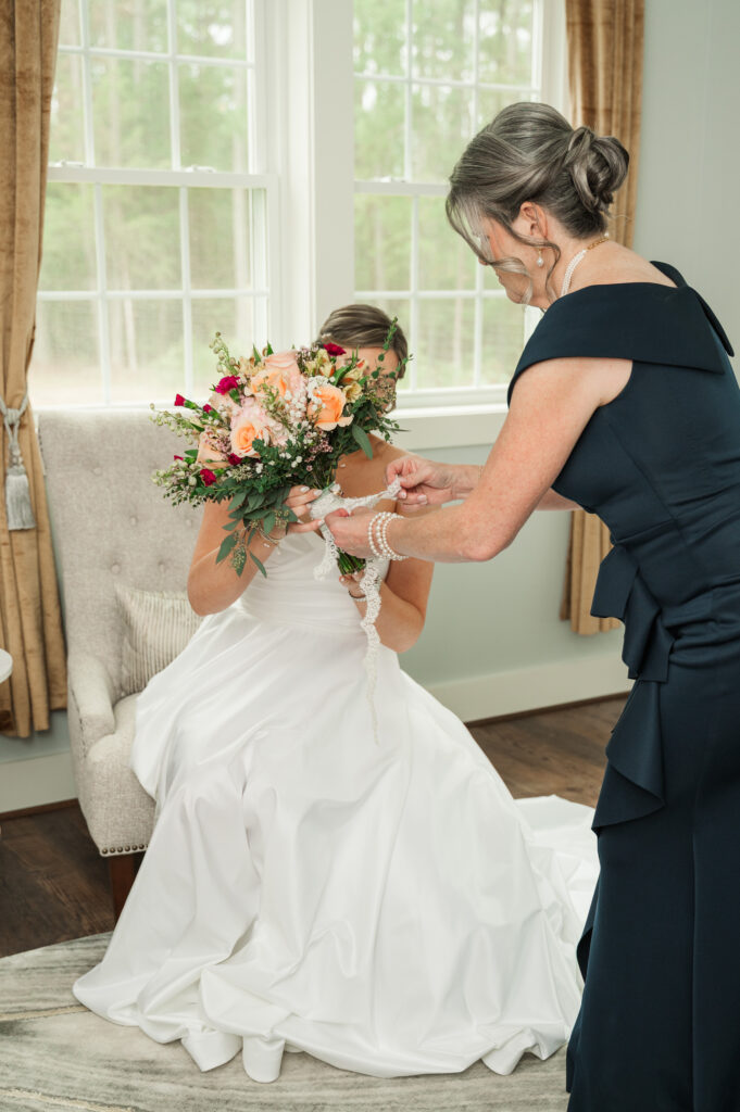 Maddy's mom tying her lace and grandmother's ring on bouquet