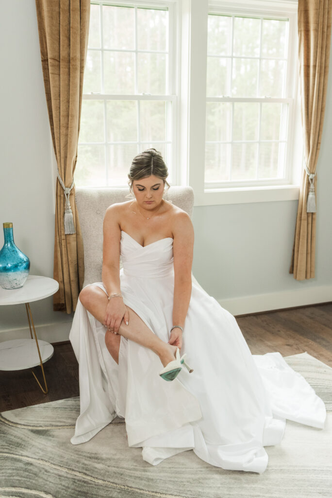 putting wedding shoes on bride